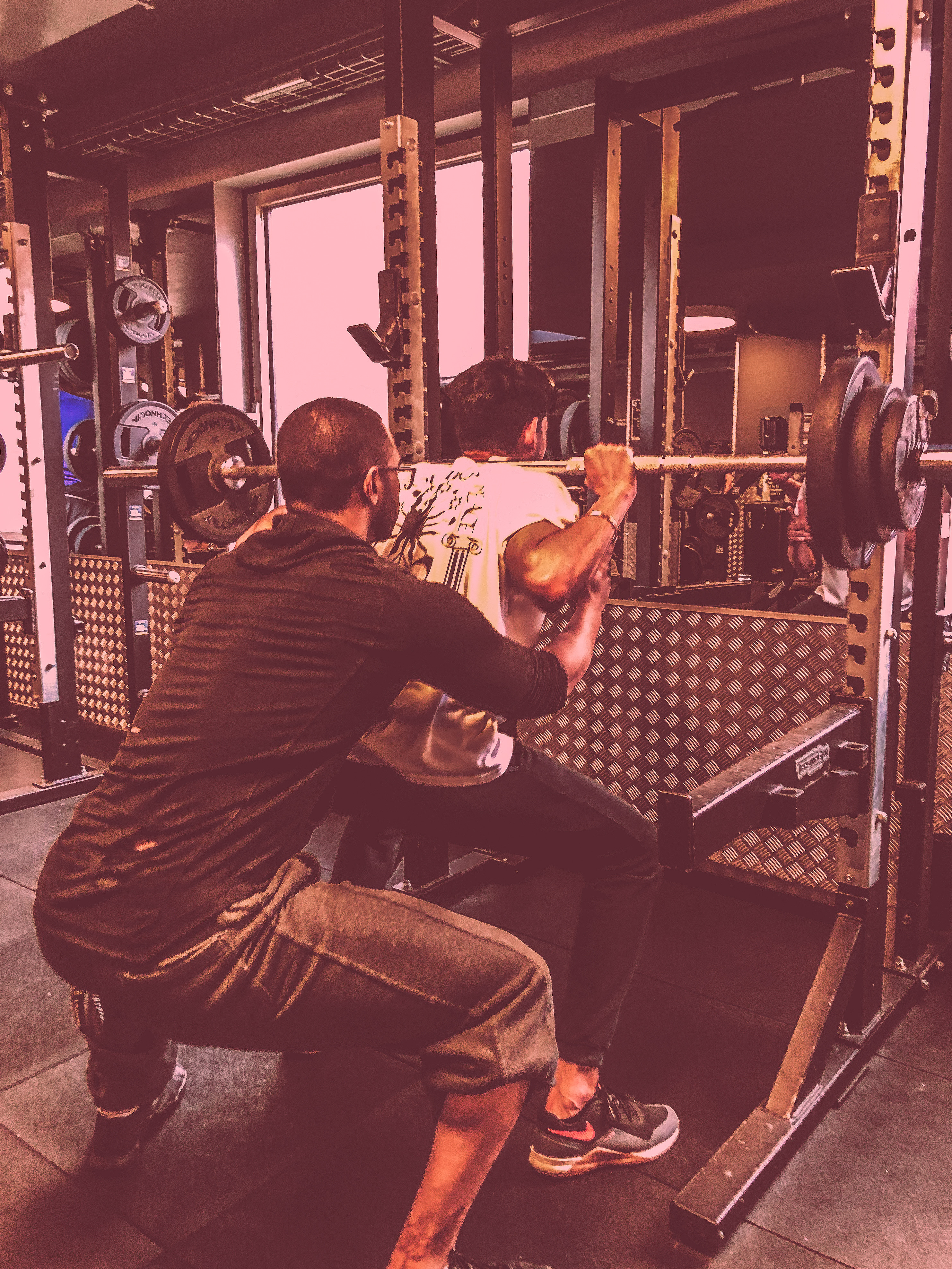 Je sécurise un squat en cage pendant une séance de coaching.